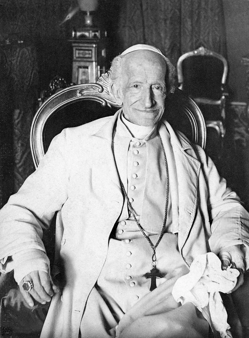 Pope Leo XIII, seated in a carved chair in white cassock and pectoral cross